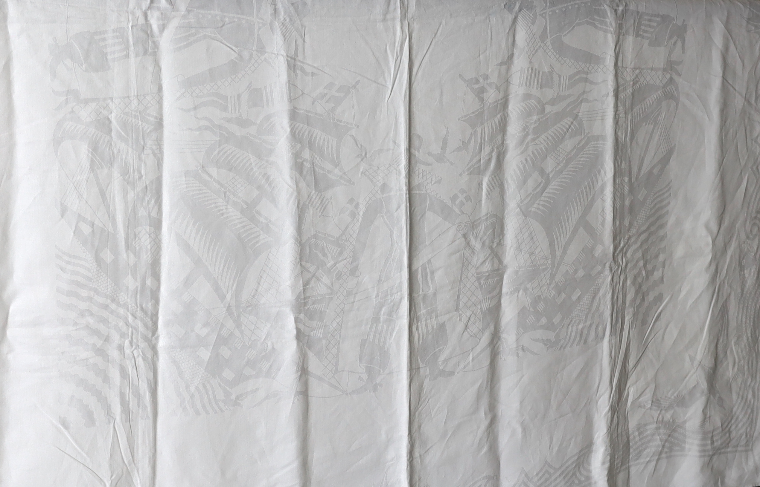 An early 20th century white linen damask table cloth, the design partly inspired by William de Morgan with galleons and fin backed fish in swirling water and tall figures with scrolls, possibly a reference to the Pilgrim